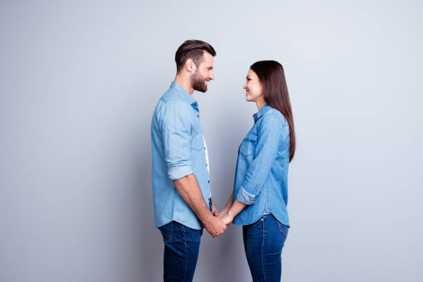 Concept of love. Two young happy people with beaming smile standing face-to-face and holding hands  face to face stock pictures, royalty-free photos & images