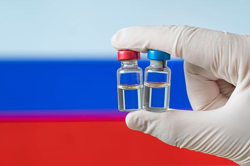 Russia flag with Coronavirus Covid-19 concept. Doctor with protection medical gloves holding a vaccine bottle. Corona virus outbreaking. concept of mass vaccination against covid 19 coronavirus