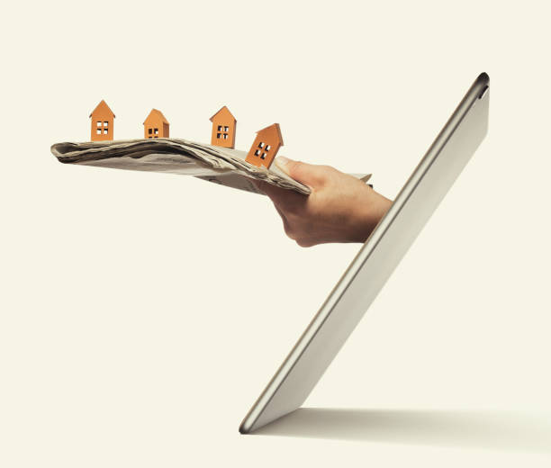 Concept of modern technologies in real estate industry. Newspaper with paper houses stick out of a tablet pc screen. Buying a house via internet. Concept of modern technologies in real estate industry. mobile real estate stock pictures, royalty-free photos & images