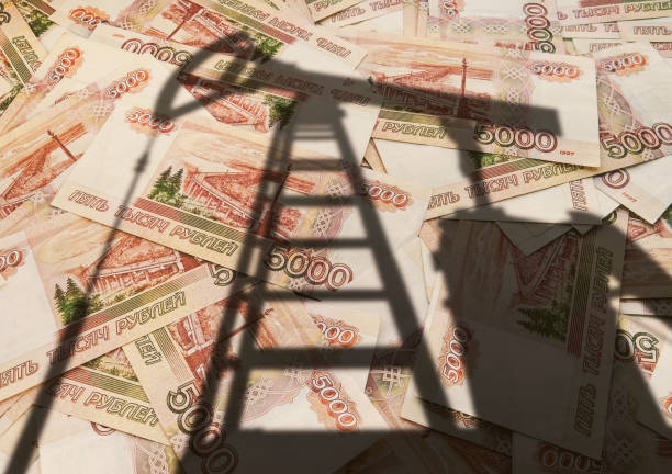 concept of selling minerals for Russian rubles. The shadow of the oil rig against the background of Russian money. Earn money from mining gas and oil energy resources stock photo