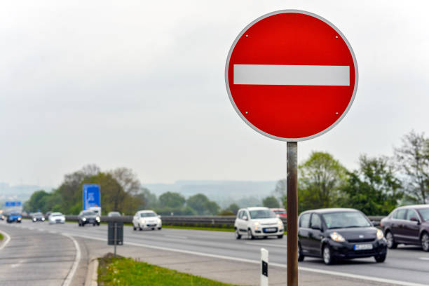 高速道路上のコンセプト間違った出口:フォアグラウンドで停止標識を持つ交通の方向に対するドイツのアウトバーン高速道路のビュー、いくつかの車 - 一方通行 ストックフォトと画像