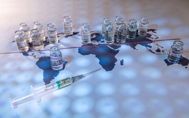 A conceptual image of a world globe map with vials for the global SARS/COVID pandemic vaccine war, with vaccine hoarding, restricting equal access to vaccines across the world, caused by vaccine nationalism and lack of vaccine solidarity stock photo