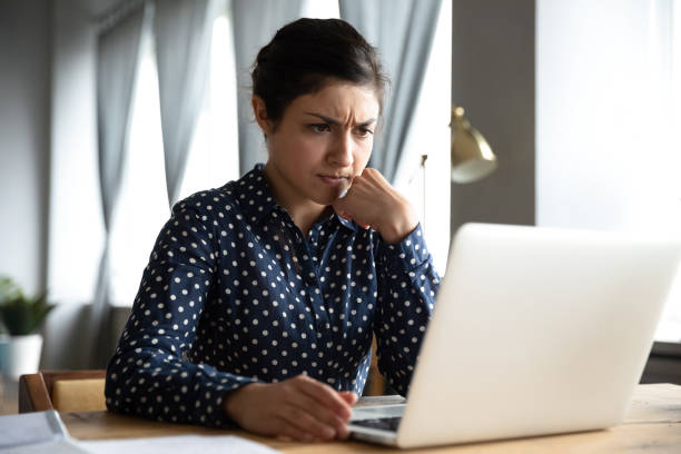 concerned indian woman look at laptop frustrated about computer problem - preocupado imagens e fotografias de stock
