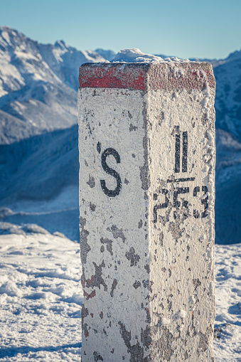 Concrete border sign of Poland and Slovakia. Sunny day in Tatra Mountains. Old red and white paint on the structure. Selective focus on the details, blurred background.