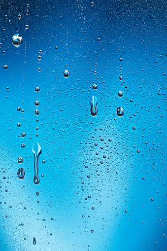 Condensation or raindrop on glass  Ice Cold frosted glass With Water Drops on blue backgrounds