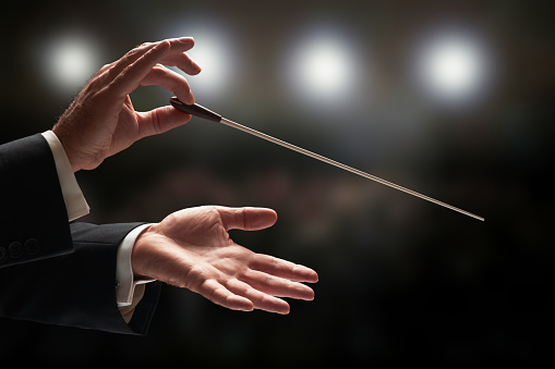 Conductor conducting an orchestra with audience in background