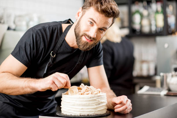 Confectioner decorating a pie Handsome confectioner in black t-shirt decorating a pie at the bar of the modern cafe interior confectioner stock pictures, royalty-free photos & images