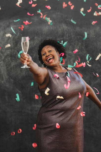 konfetti fällt auf eine lachende afroamerikanerin mit champagner - einzelne frau über 40 stock-fotos und bilder