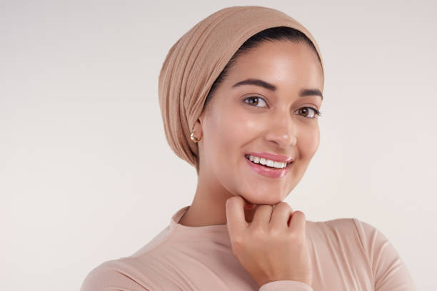 Confidence is in the smile Studio shot of a beautiful young woman resting her chin on her hand and smiling against a beige background beautiful arab woman stock pictures, royalty-free photos & images