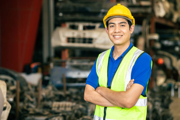 자신감 아시아 남성 엔지니어 노동자 서 팔은 공장에서 일하는 것을 즐기기위해 행복한 미소를 지었습니다. - labor day 뉴스 사진 이미지