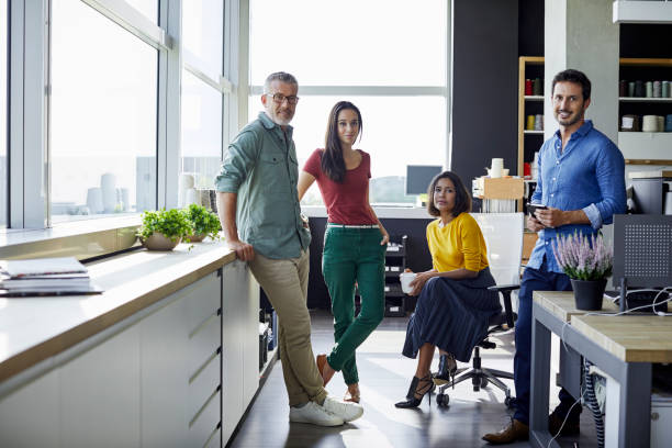 Confident business people in office Full length of confident business people in office. Male and female coworkers are in smart casuals. They are at textile industry. four people stock pictures, royalty-free photos & images