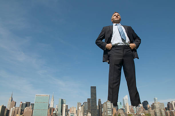 Confident Businessman Giant Towering Over City Skyline stock photo