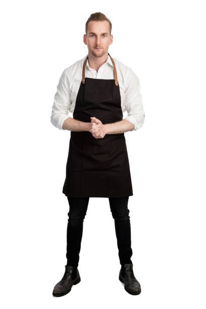 Confident chef in white shirt and black apron Blonde attractive chef wearing a white shirt and black apron standing with his hands clasped against a white background looking at camera. apron stock pictures, royalty-free photos & images