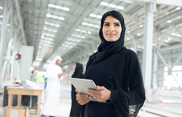 Confident Female Construction Manager Confident Arab woman dressed in abaya looking forward while holding a digital tablet. abaya clothing stock pictures, royalty-free photos & images