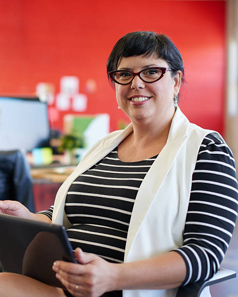 confident female designer working on a digital tablet in red - chubby women office manager bildbanksfoton och bilder