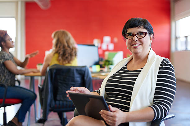 confident female designer working on a digital tablet in red - chubby women office manager bildbanksfoton och bilder