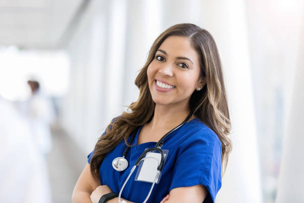 Confident female doctor Portrait of young Hispanic female healthcare professional smiling at the camera. She is standing with her arms crossed. nurse face stock pictures, royalty-free photos & images
