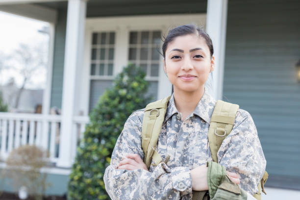 Confident female soldier Confident young female soldier is ready for her first overseas deployment. She is standing in front of her home. worker returning home stock pictures, royalty-free photos & images