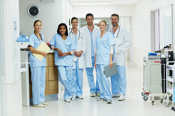 Confident healthcare workers standing in hospital Portrait of confident doctors and nurses standing together in hospital medical scrubs photos stock pictures, royalty-free photos & images