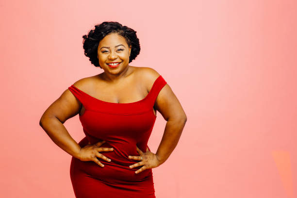 Confident in my body / Portrait of a happy, curvy young woman in red dress stock photo