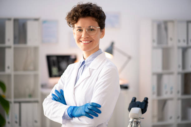 Confident laboratory researcher Portrait of positive confident female laboratory researcher in goggles and white coat standing with crossed arms scientist stock pictures, royalty-free photos & images