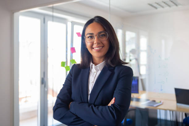 Confident Latin business leader portrait Confident Latin business leader portrait. Young businesswoman in suit and glasses posing with arms folded, looking at camera and smiling. Female leadership concept medium shot stock pictures, royalty-free photos & images