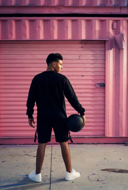 zekere latijnse tiener die een basketbal houdt - basketball player back stockfoto's en -beelden