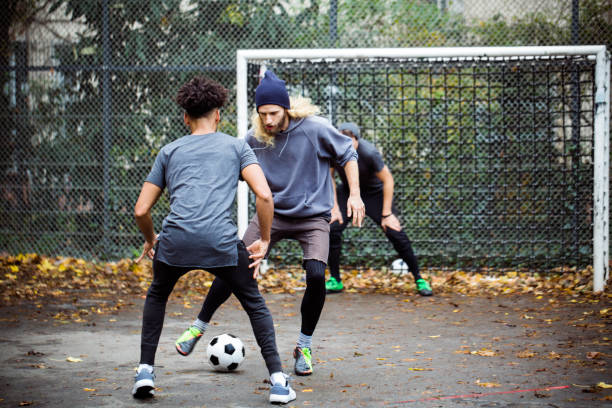 Confident man dribbling ball from opponent Confident young man dribbling ball from opponent. Player is standing at goal post. They are in sportswear. defending sport stock pictures, royalty-free photos & images