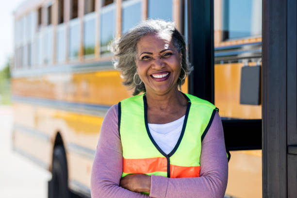 Confident mature female bus driver Portrait of smiling mature female bus driver looking confidently at the camera. She is standing in front of a school bus. school bus driver stock pictures, royalty-free photos & images