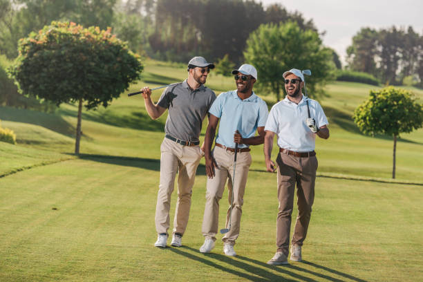 自信を持って笑顔男性キャップとサングラス ゴルフ クラブを押しながら芝生の上を歩く - ゴルフ　服装 ストックフォトと画像