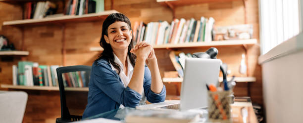 Confident young businesswoman smiling in her home office stock photo