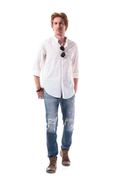 jeune homme élégant de beau confiant marchant et regardant l’appareil-photo avec des mains dans des poches arrière - chemise en jeans poche photos et images de collection
