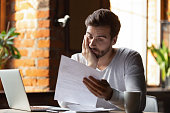 Confused frustrated young man reading letter in cafe, debt notification, bad financial report, money problem, money problem, upset student receiving bad news, unsuccessful exam or test results