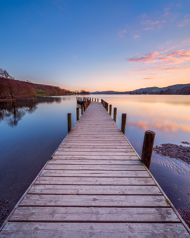 Sunset at a wooden jetty on Coniston Water in the English Lake District with a colourful sky