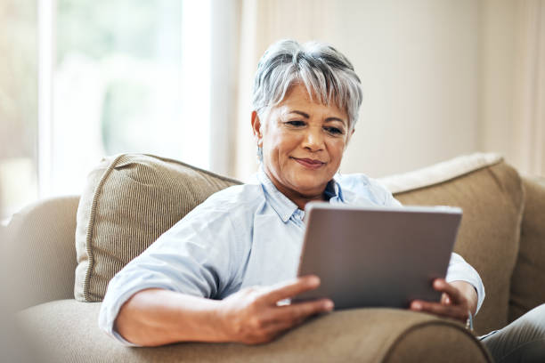 terhubung di rumah dalam masa pensiunnya - menggunakan tablet digital potret stok, foto, & gambar bebas royalti