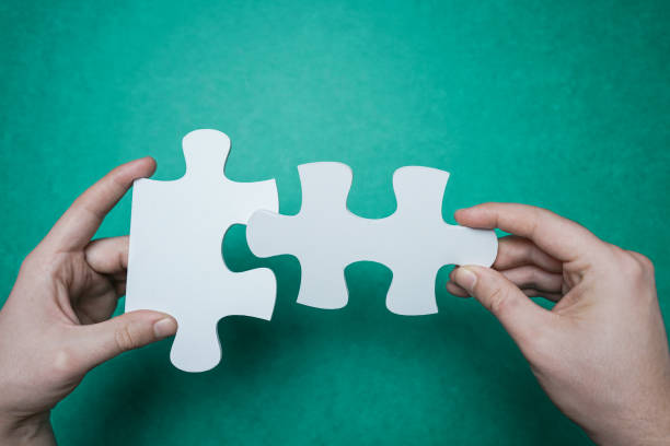 Connection. Hands trying to fit two puzzle pieces together. stock photo