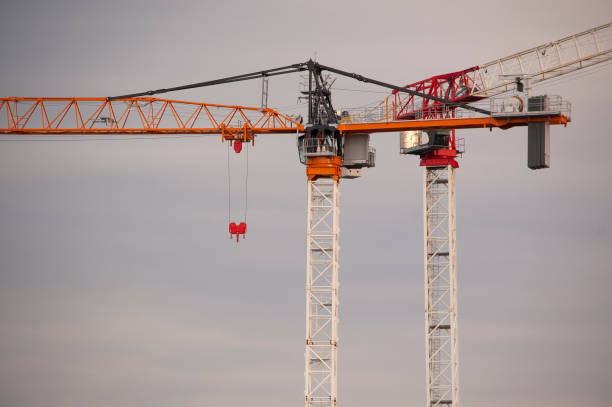 2 construction cranes against clouds stock photo