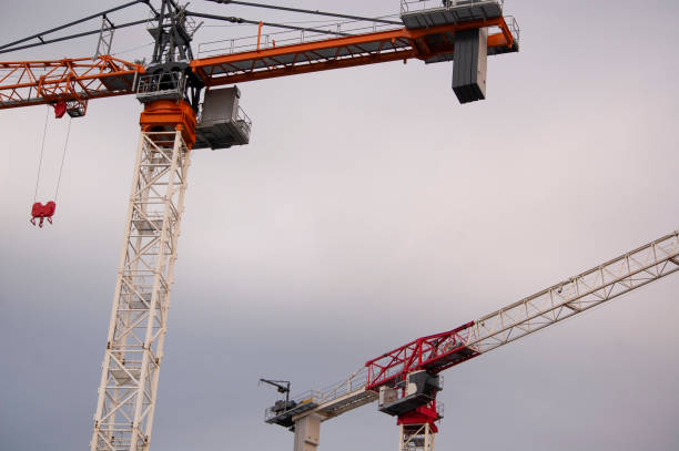 2 construction cranes, arms pointing in opposite directions stock photo