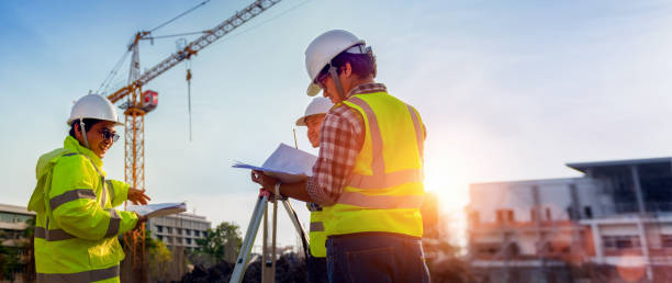 Construction engineers discussion with architects at construction site or building site of highrise building with Surveying for making contour plans is a graphical representation of the lay in land. stock photo