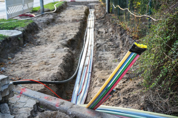 Construction site for installing fiber optic cables under the ground beside a street to bring fast internet to all residents, selected focus stock photo