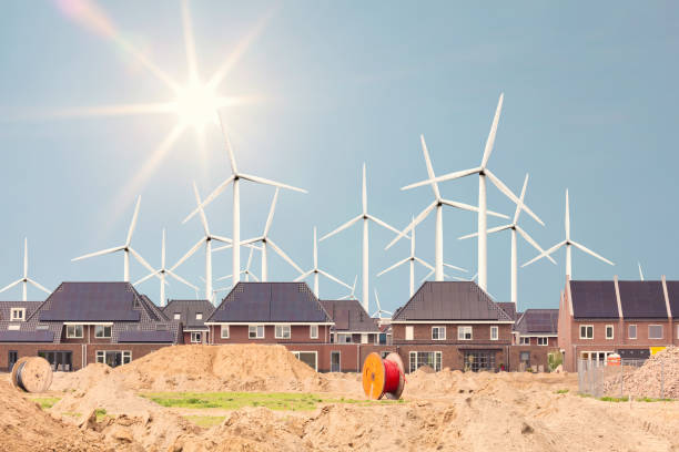 Construction site of new Dutch family homes with large wind turbines and sun in the background stock photo