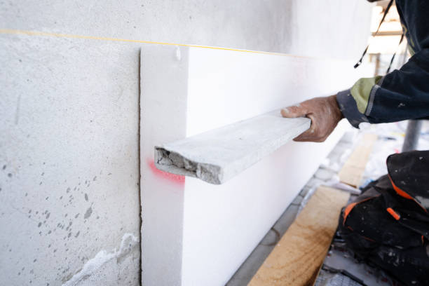 bouwvakker tijdens de styrofoam huis externe wand isolatie. aannemer met niveau controle van het werk in progress niveau van de boards - polystyreen stockfoto's en -beelden