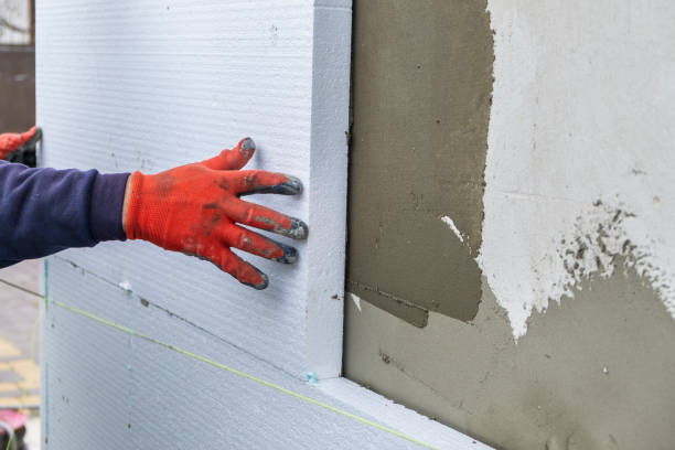 Construction worker installing styrofoam insulation sheets on house facade wall for thermal protection. stock photo