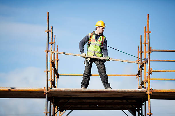 Construction worker setting up scaffolding against the sky Construction worker setting up scaffolding. animal harness stock pictures, royalty-free photos & images