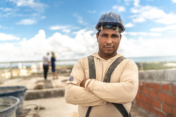 Construction worker standing with arms crossed in a construction site Construction worker standing with arms crossed in a construction site pardo brazilian stock pictures, royalty-free photos & images