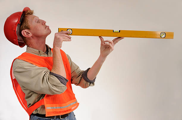 Construction worker stares down spirit level stock photo