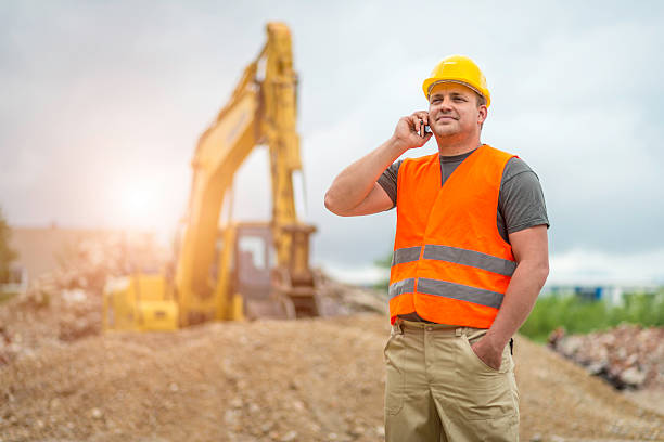 Construction worker takes a call Construction worker on the phone at the construction site waistcoat stock pictures, royalty-free photos & images