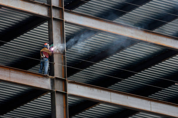 construction worker welding beam on high rise building - girder stockfoto's en -beelden