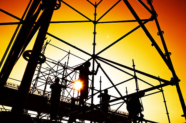 Construction workers on scaffolding at dawn stock photo