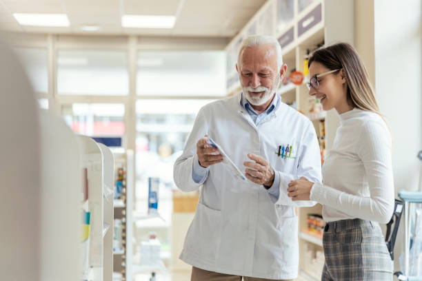 Consultation with a professional, conversation between the pharmacist and the client. A mature man explains drug therapy to a client. An experienced pharmacist recommends therapy to the client stock photo